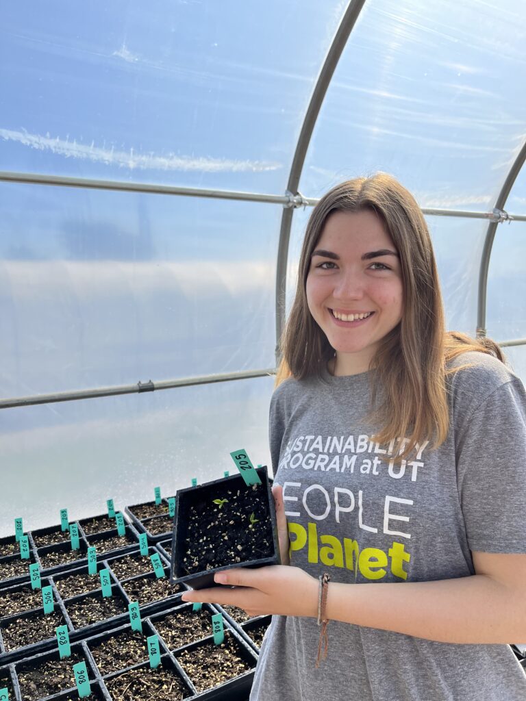 Rachel Hefton in a greenhouse holding a sample