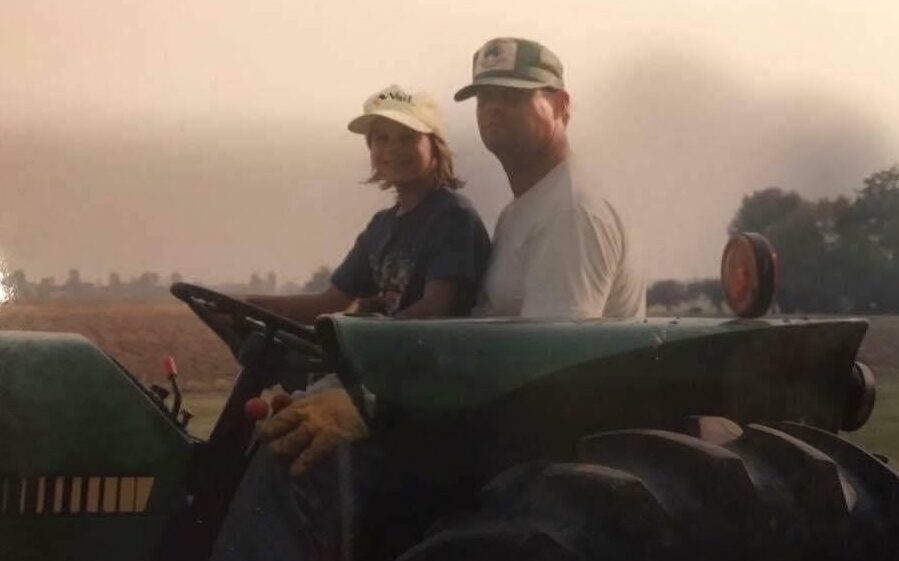 Karen DeLong as a child on a tractor with her father