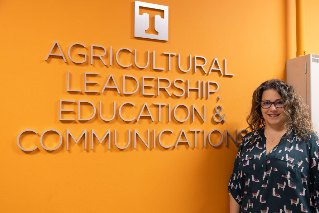 Jennifer Richards standing in front of a sign for the Department of Agricultural Leadership, Education and Communications