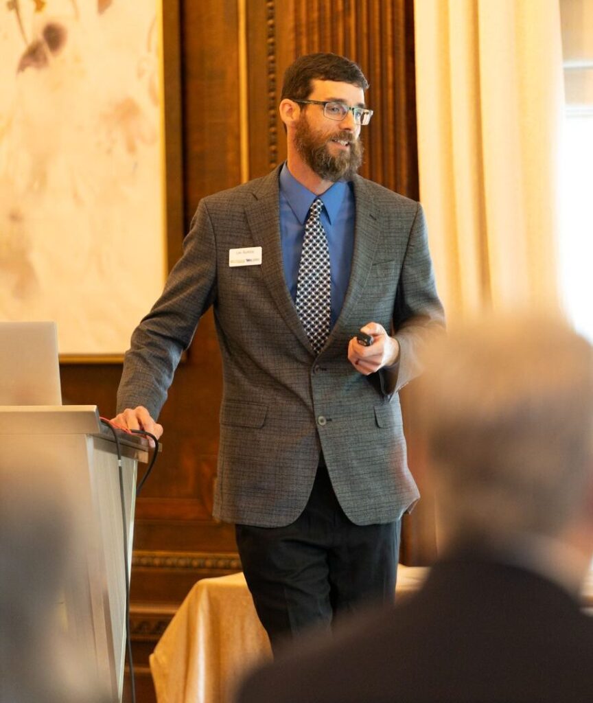 Lee Rumble in a suit speaking to a crowd
