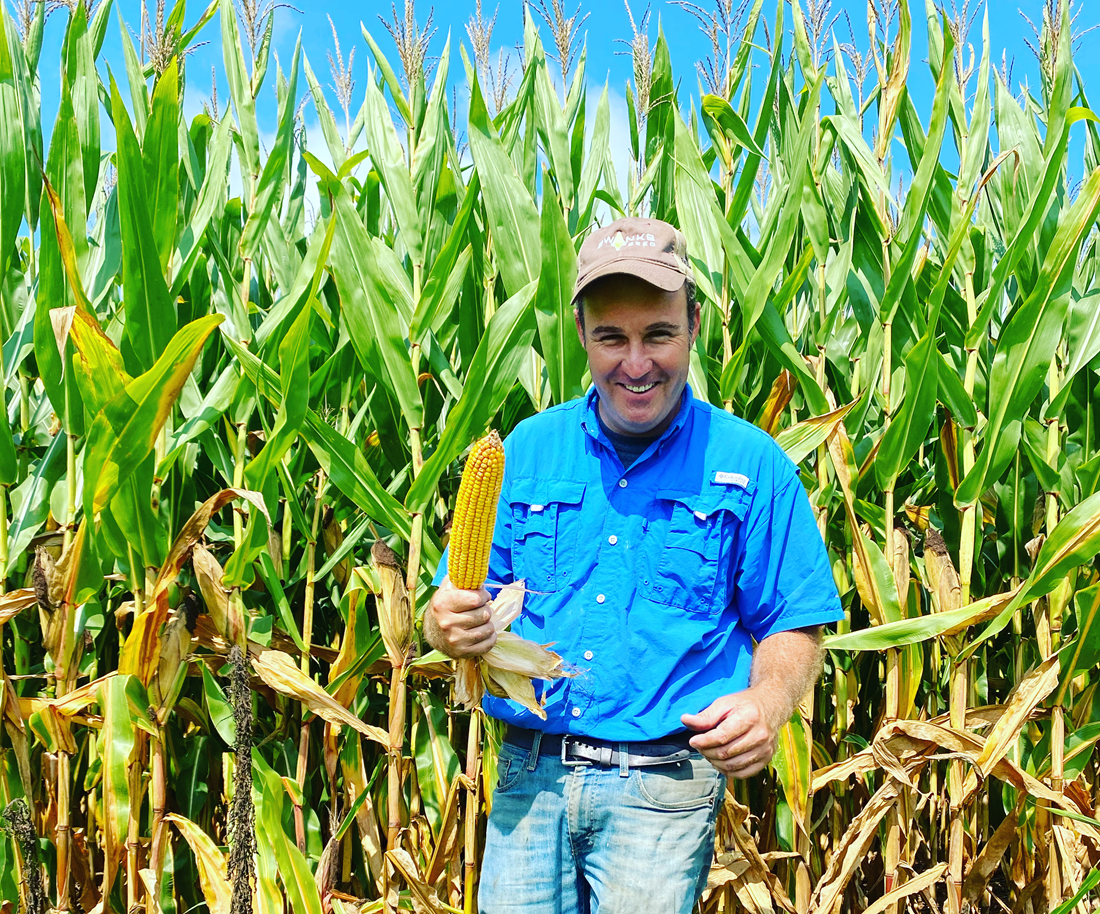 Jonathan Walton holding corn in front of a corn field