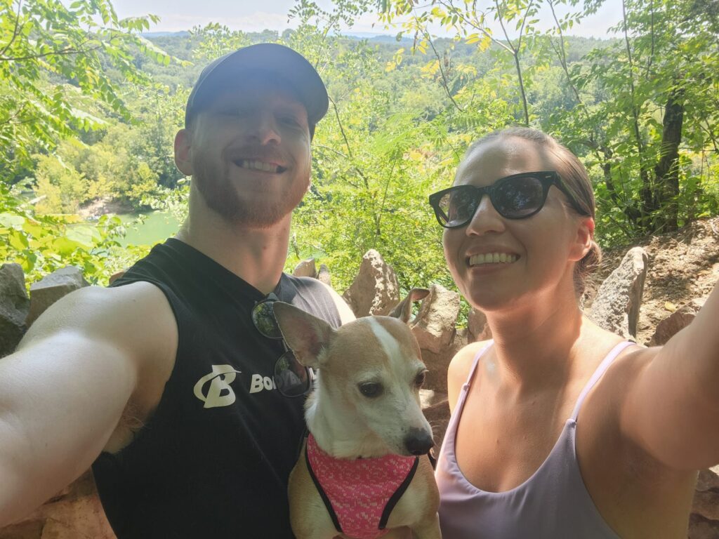 Katherine Lopez poses for a selfie with her fiance and dog while outside on a hike.