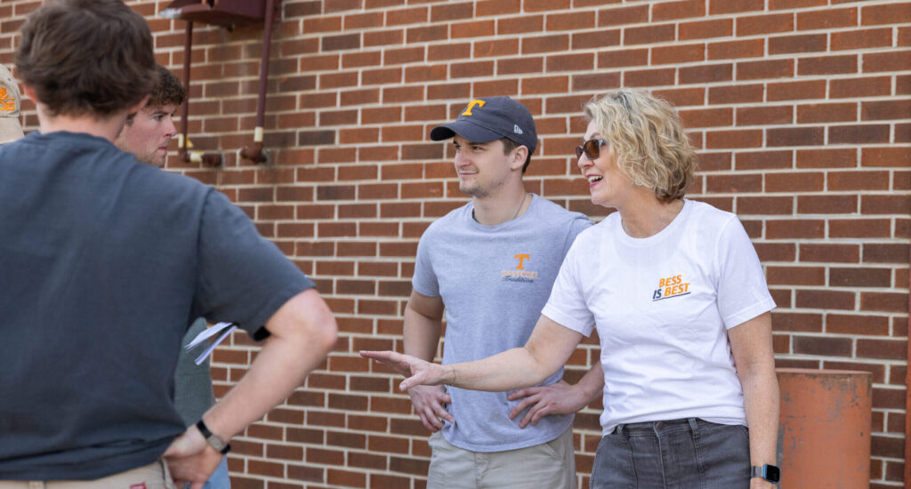 Angela Smith smiles as she interacts with three students outside of a brick building.