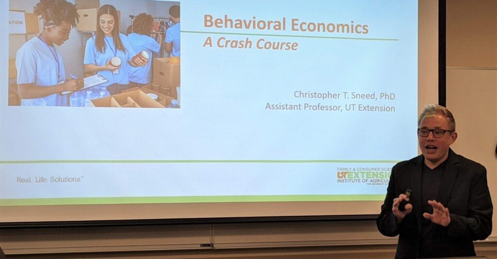Christopher Sneed is giving a presentation with the title "Behavioral Economics: A Crash Course."