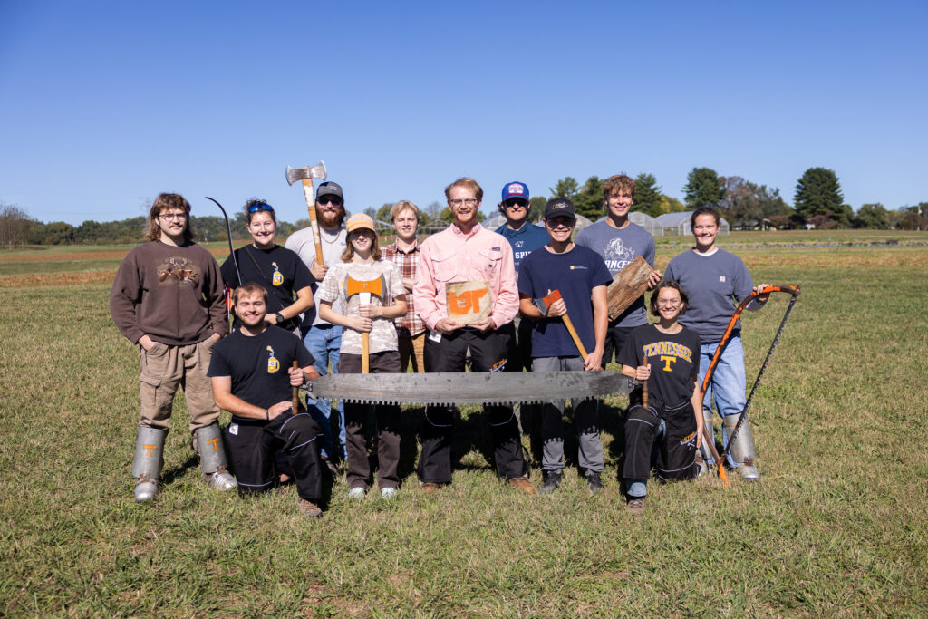 Group photo of the Forestry Club's Timbersports Team with members holding a variety of equipment including saws, axes and a bow and arrow.