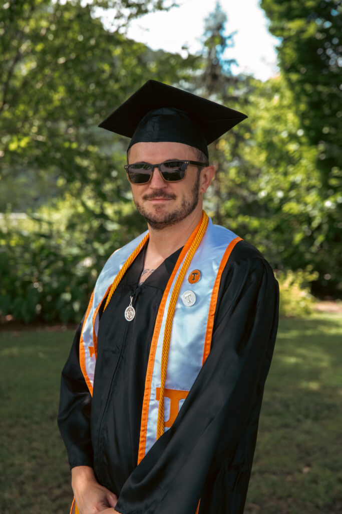 Jimi Miller with sunglasses on in graduation attire