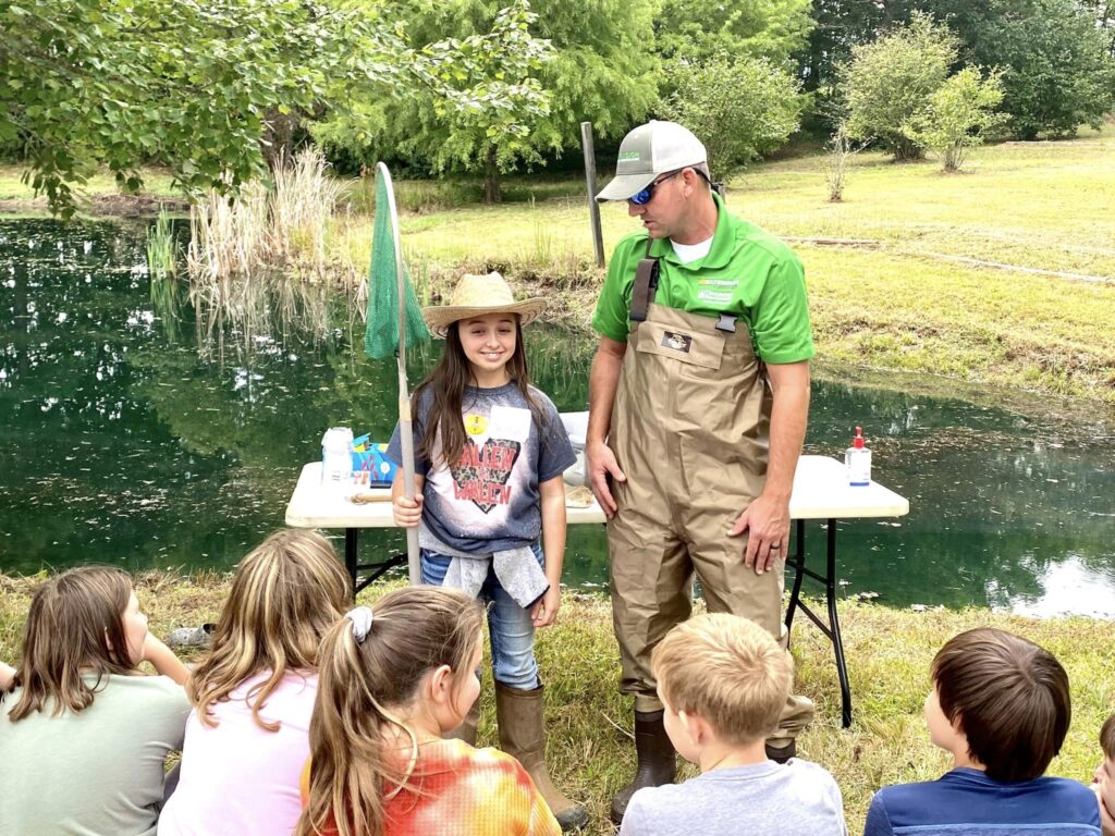 Creig Kimbro with a group of students teaching them about fish ponds