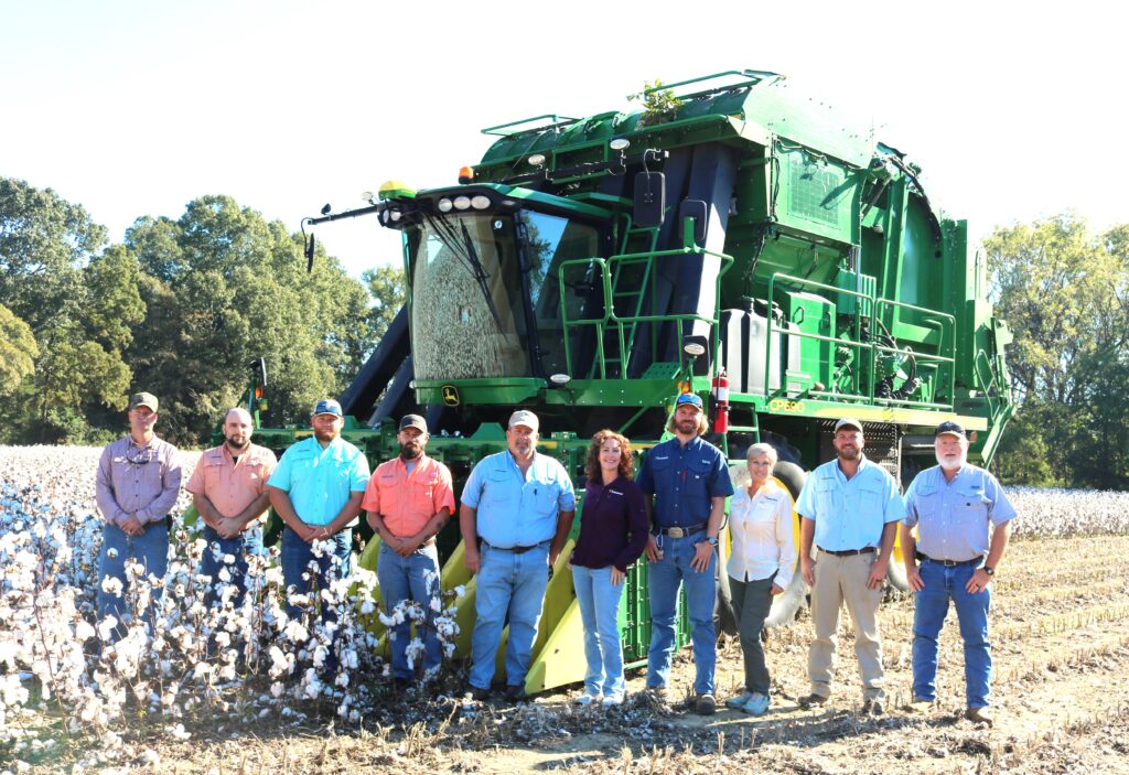 Blake Brown and his team standing in front of a cotton picking machine