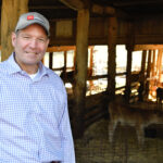 Charlie Hatcher at a barn with cattle in the background
