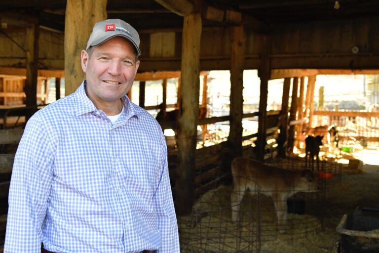 Charlie Hatcher at a barn with cattle in the background