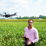 Elias in a field controlling a drone flying above