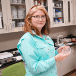 Claire in the lab holding up a Petri Dish