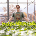 Jacob Friedrich standing behind plants in a greenhouse