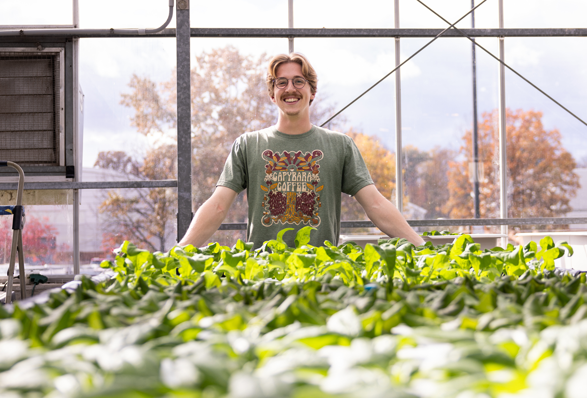 Jacob Friedrich standing behind plants in a greenhouse