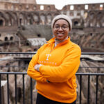 Kyra Barrier wearing a bright orange Tennessee sweater stands inside the Colosseum in Rome, Italy.