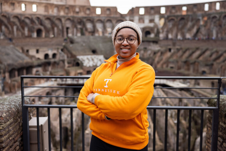 Kyra Barrier wearing a bright orange Tennessee sweater stands inside the Colosseum in Rome, Italy.
