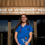 Katherine Lopez stands outside of a building labeled "College of Veterinary Medicine, University of Tennessee Institute of Agriculture."