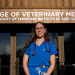 Katherine Lopez stands outside of a building labeled "College of Veterinary Medicine, University of Tennessee Institute of Agriculture."
