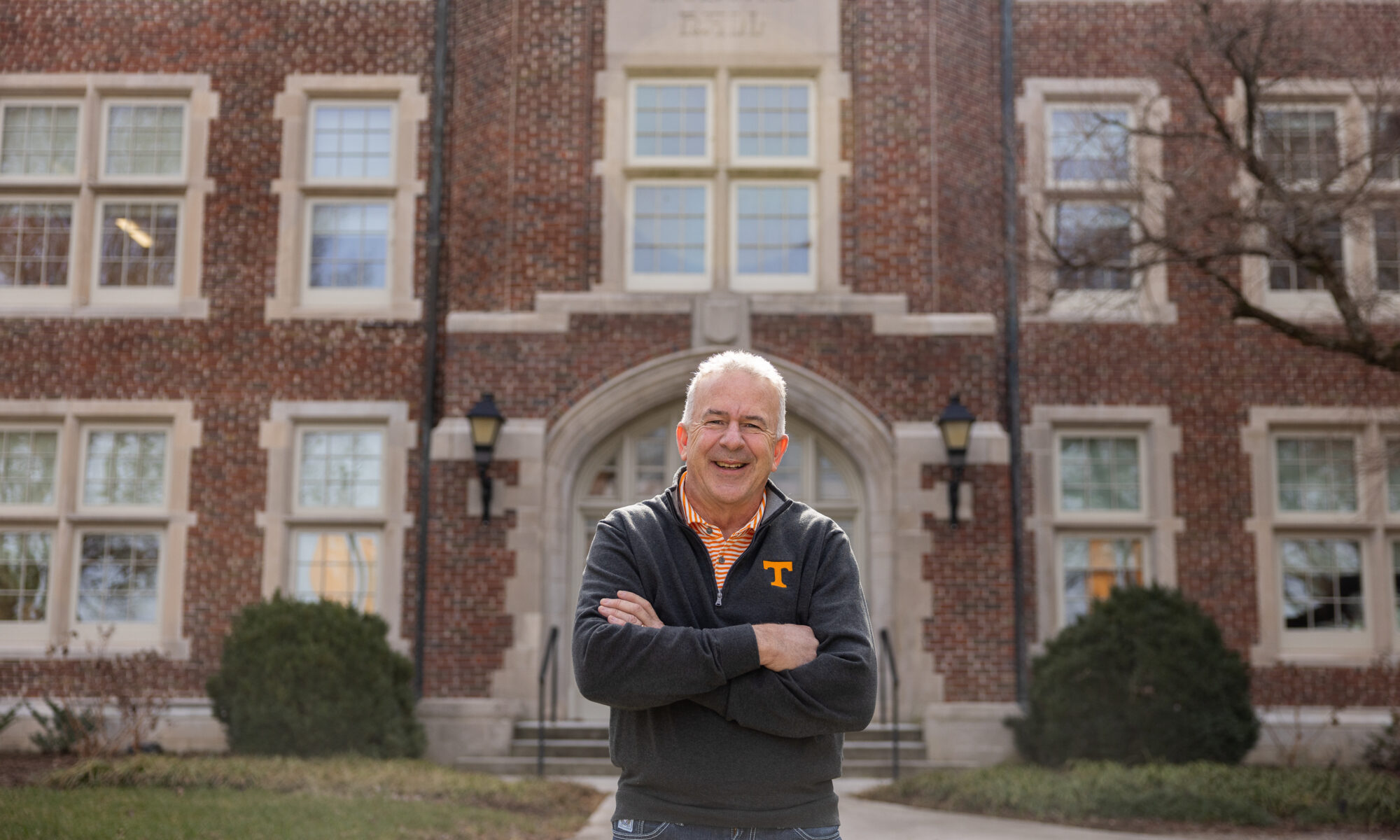 Craig Bacon smiles while wearing a UT Knoxville branded jacket and standing outside Morgan Hall.