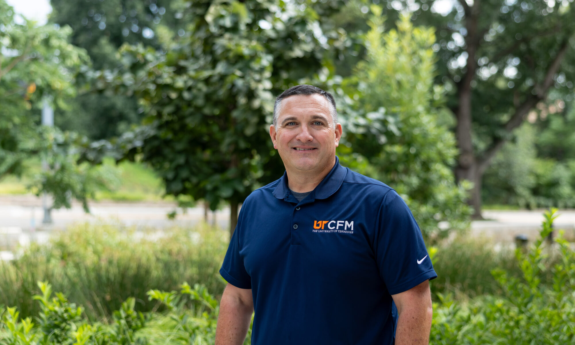 David Bilderback smiles for a photo with trees and greenery in the background.