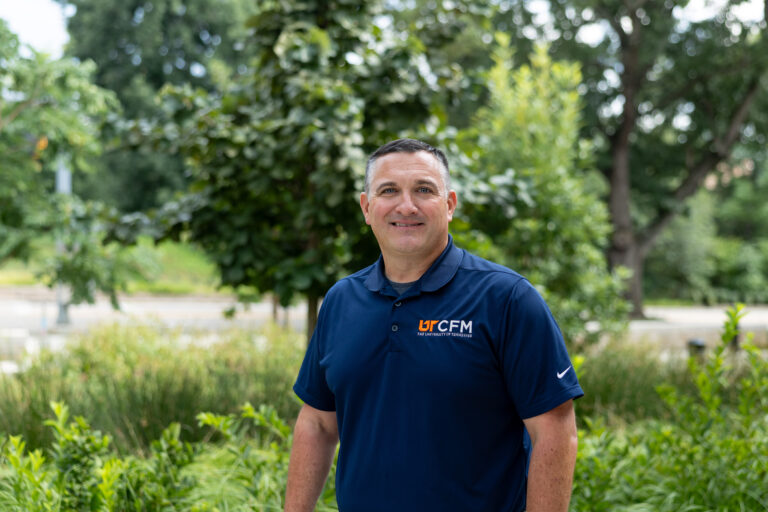 David Bilderback smiles for a photo with trees and greenery in the background.