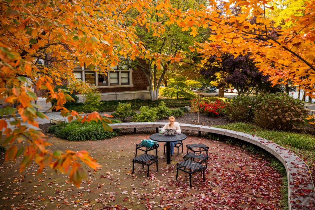 A student sitting outside of Morgan Hall with fall foliage