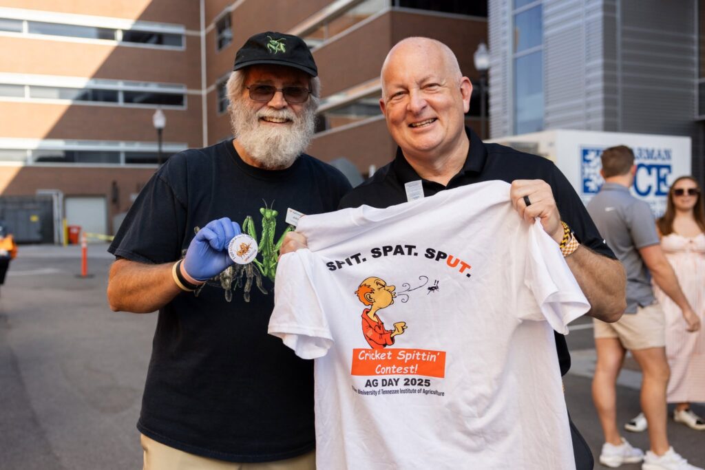 Keith Carver holding up the cricket spitting contest t-shirt with Jerome Grant