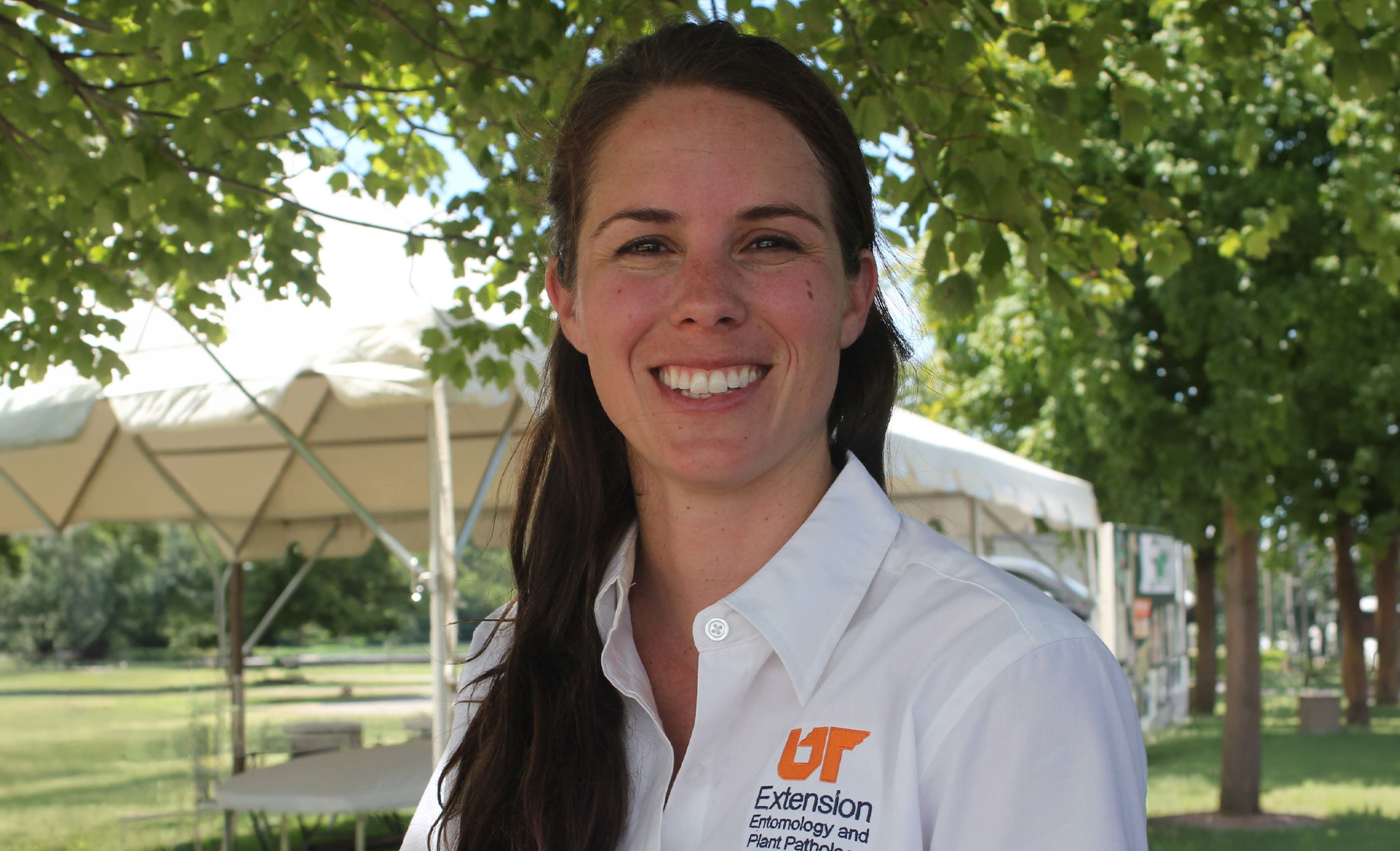 Heather Kelly smiles at the camera while wearing a white collared shirt with an orange UT logo